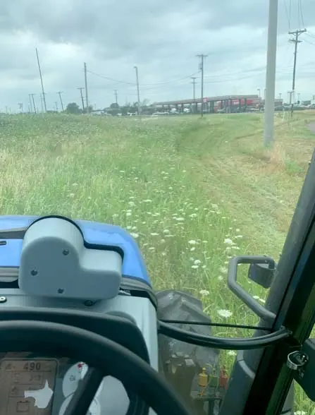Mowing a grassy commercial lot beside a road