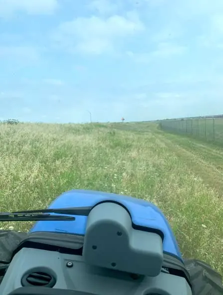Mower working along a ranch fence line